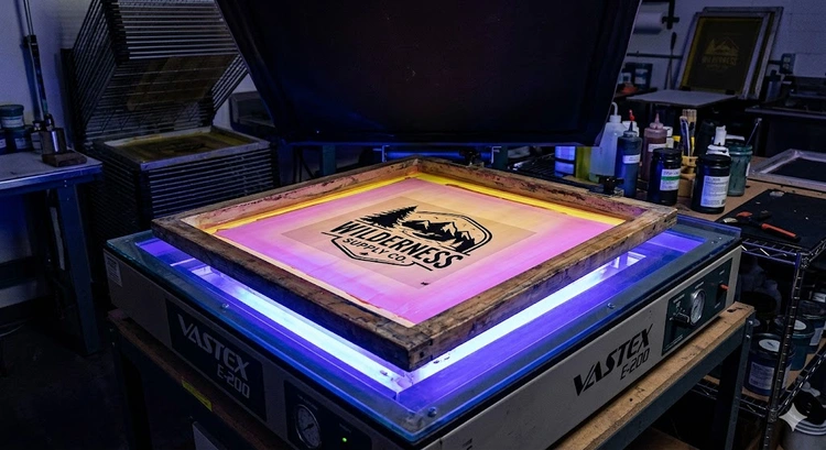 how to expose a screen for screen printing — emulsion-coated mesh under UV exposure unit with film positive in place
